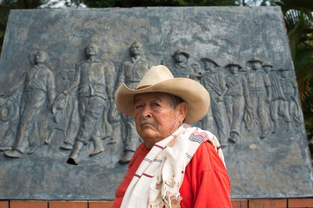 Benjamín Mateus posa frente al monumento que hicieron las autoridades de Monterrey, Casanare, para conmemorar el desarme de la guerrilla liberal en 1953. Copyright: http://pacifista.co/entrevista-con-la-historia-guerrilleros-revolucion-llanera/ .